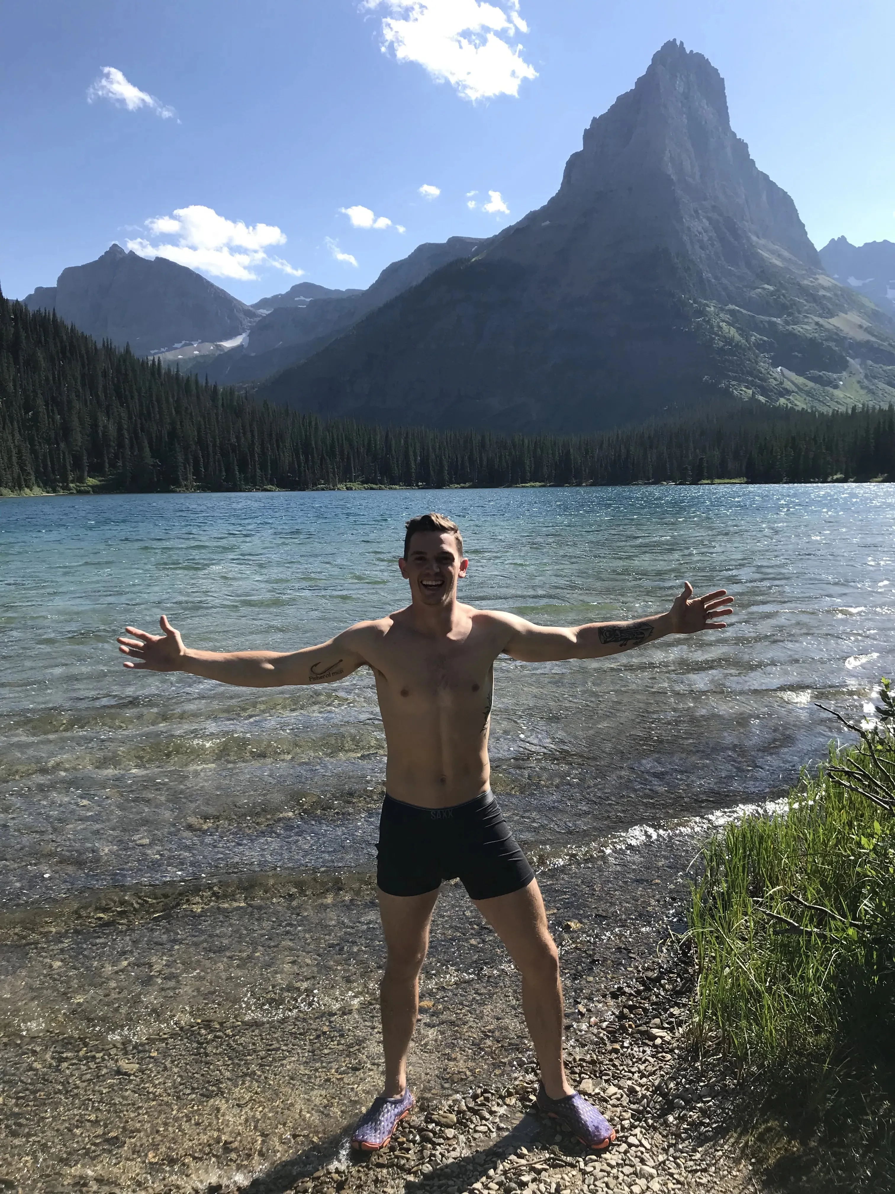 Hiker with arms open at the shore of an alpine lake