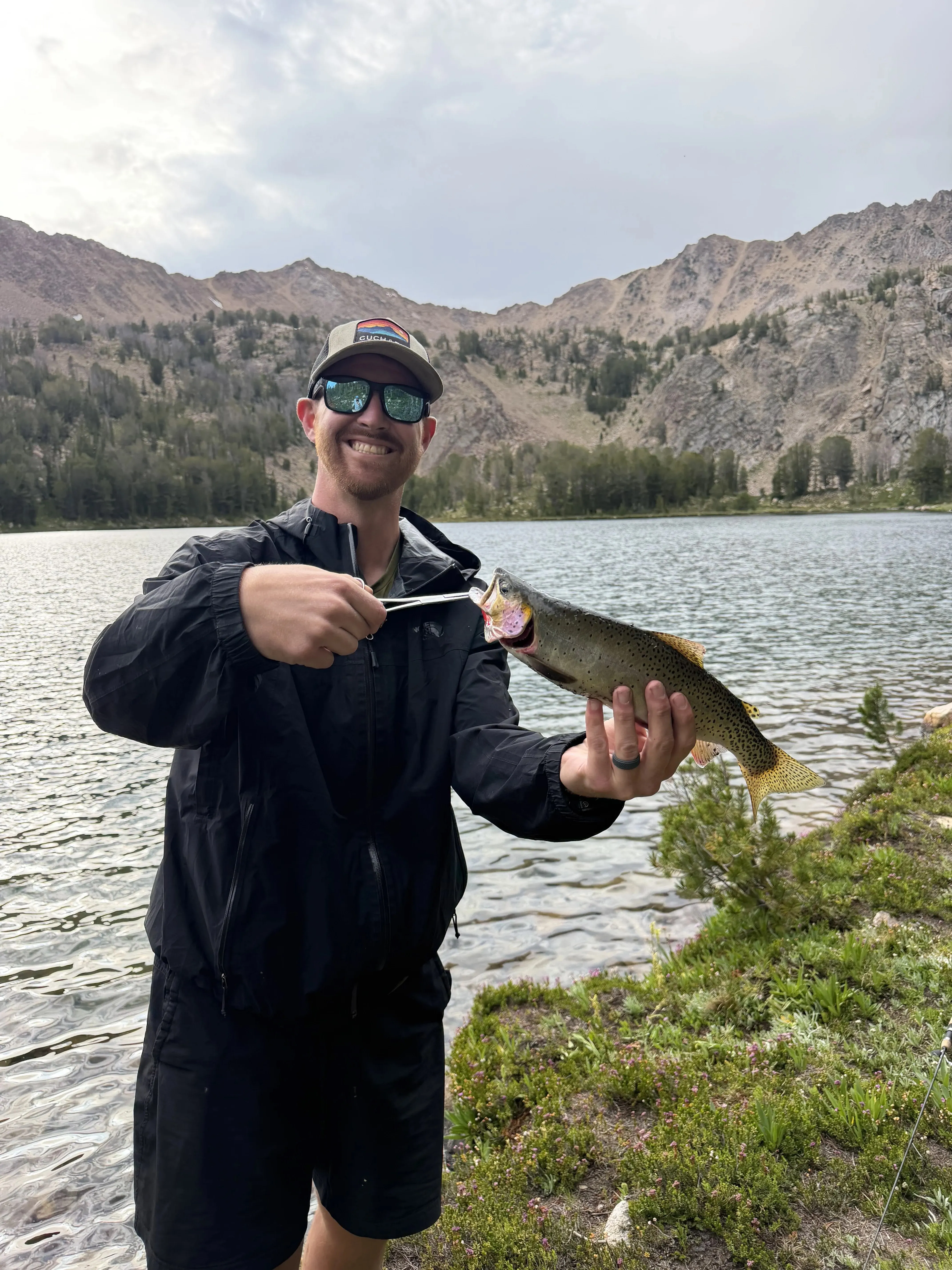 Hiker holding a cutthroat trout at an alpine lake