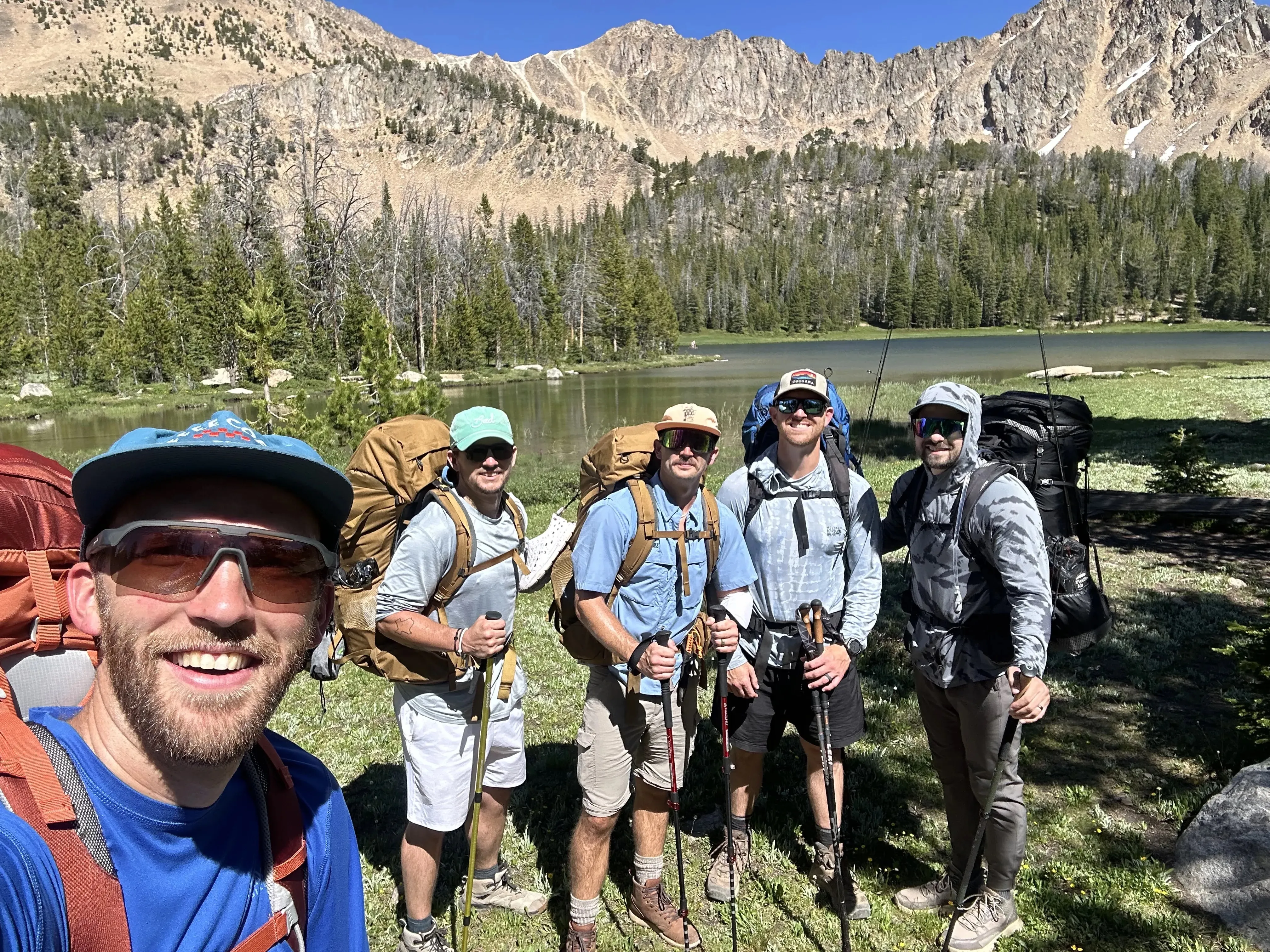 Five backpackers taking a selfie by a mountain lake