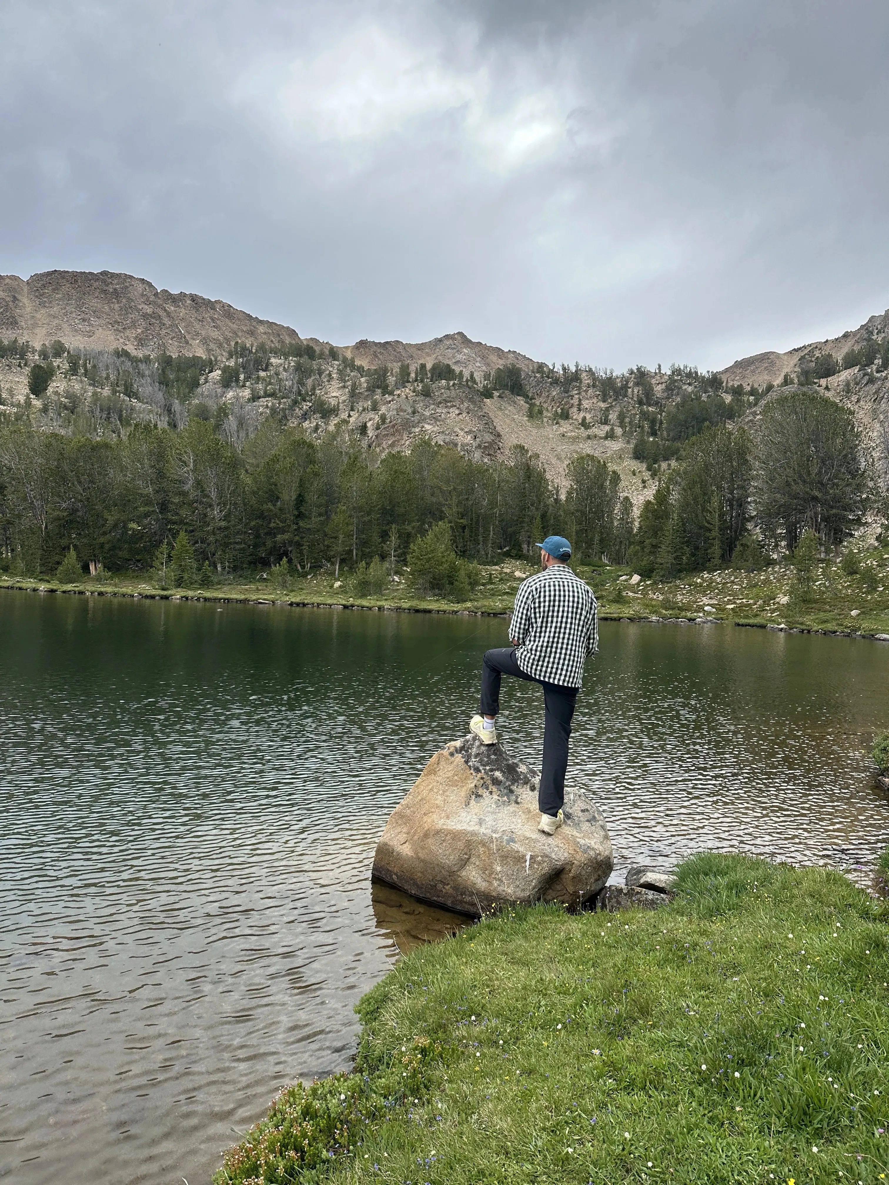 Hiker standing on a boulder overlooking an alpine lake