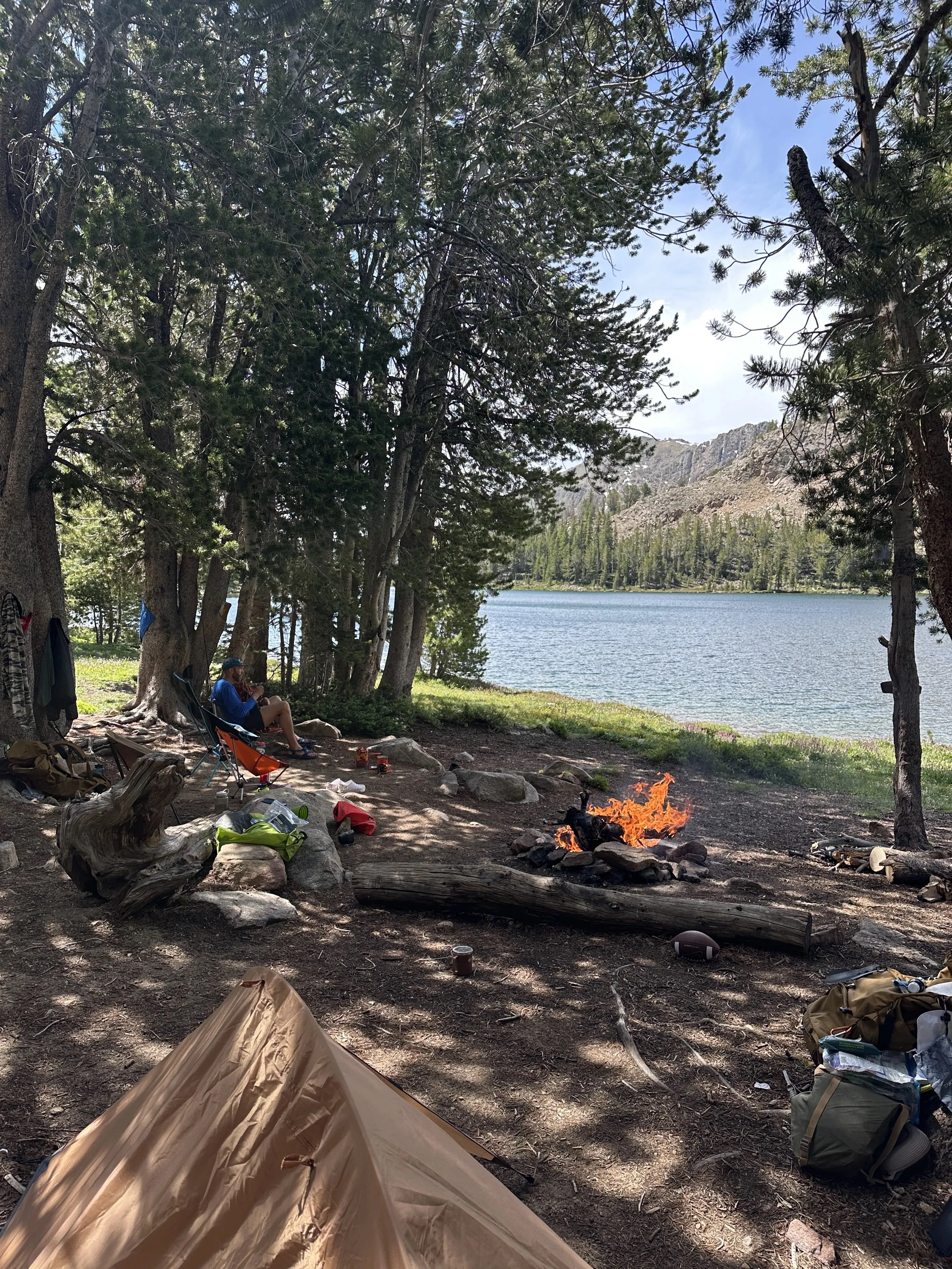 Lakeside backpacking camp with tent and fire
