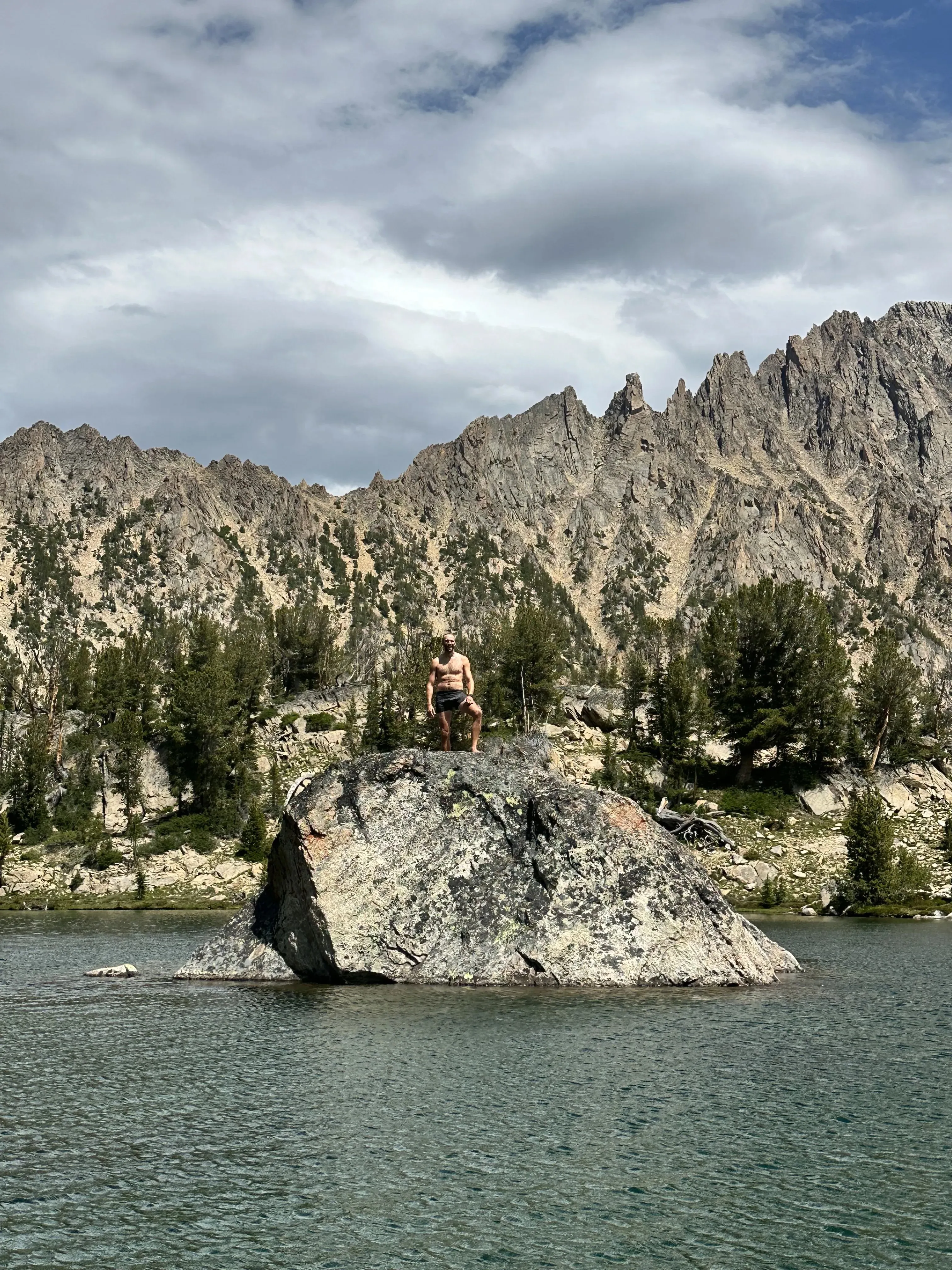 Hiker standing on a boulder in a mountain lake