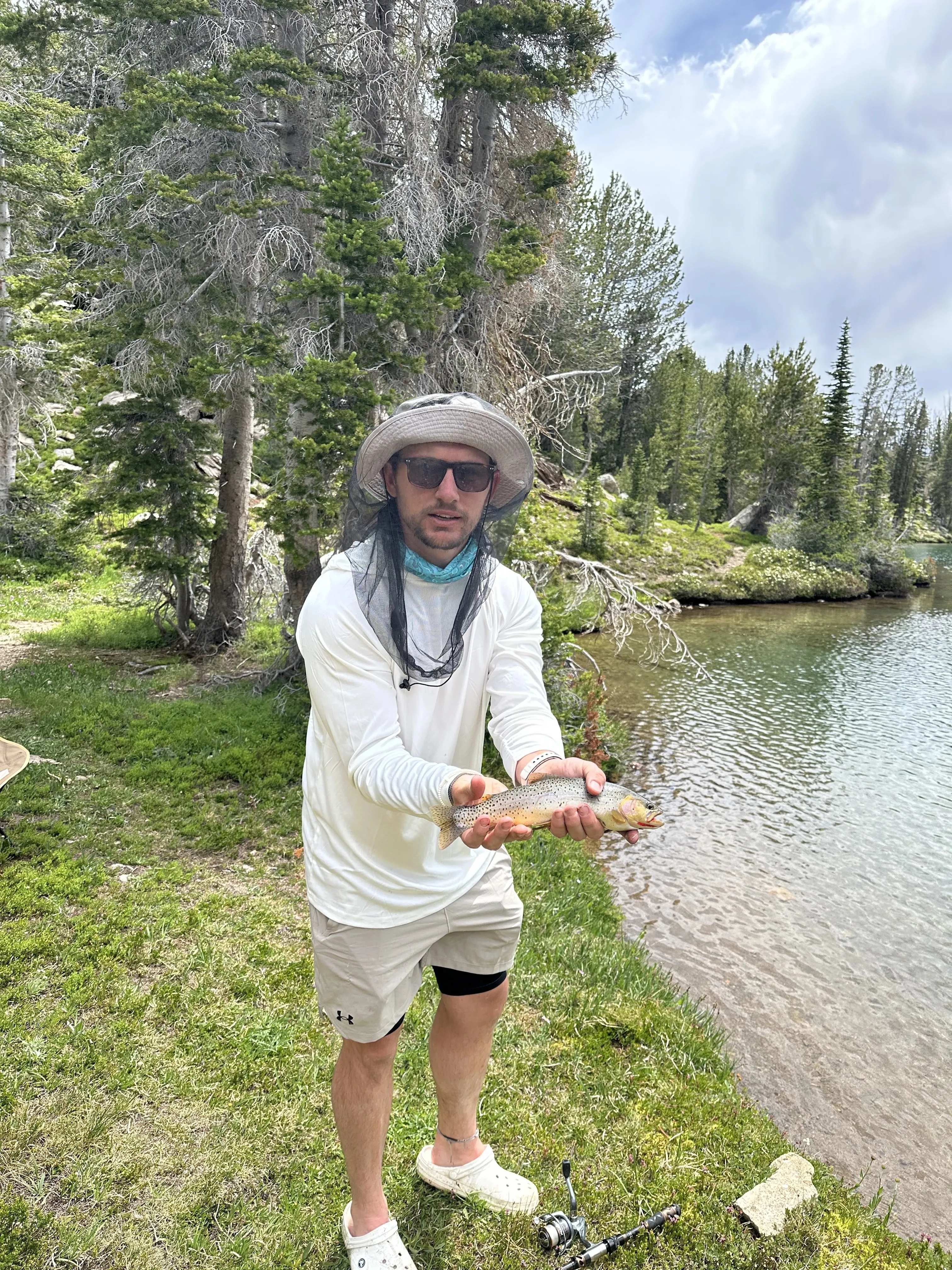 Hiker holding a trout by a mountain lake