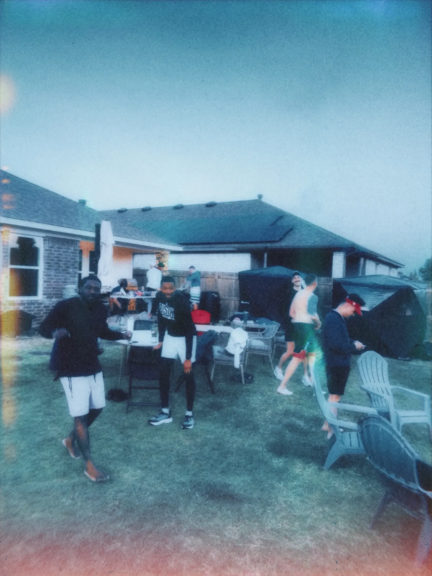 Meantime guys gathered in a backyard at dusk